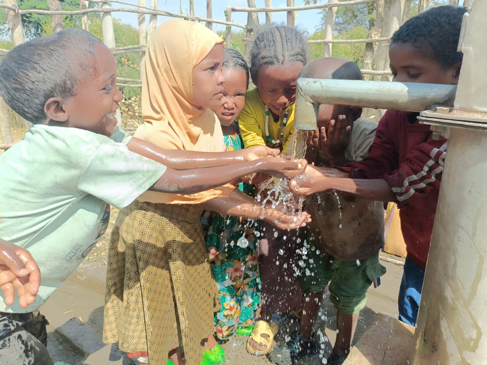 Kinderen die hun gezicht wassen bij een waterput